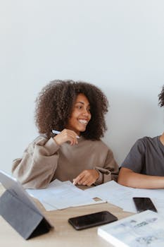 一位非洲裔美国妇女在室内微笑着学习电子设备和论文