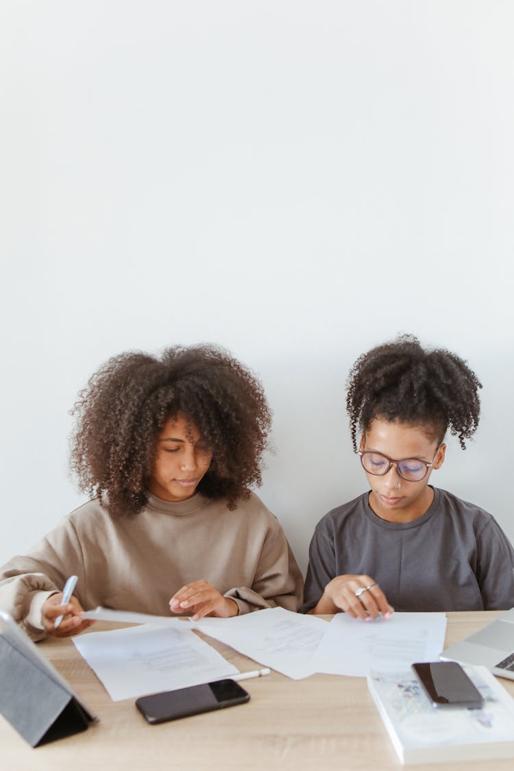 Women Sitting And Reading On A White Papers