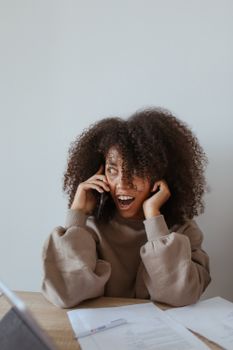 一位留着非洲发型的女子在室内用智能手机通话时显得很震惊