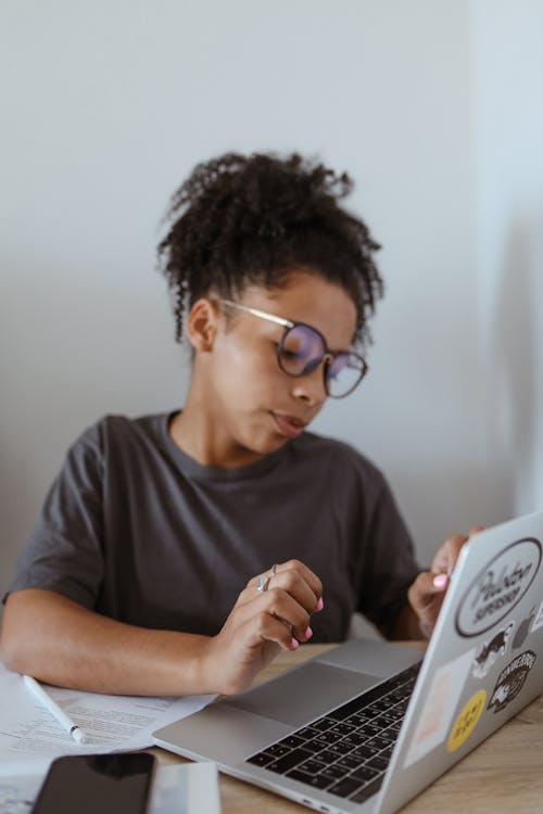 Young Woman in Gray Shirt Sitting and Using a Computer Laptop