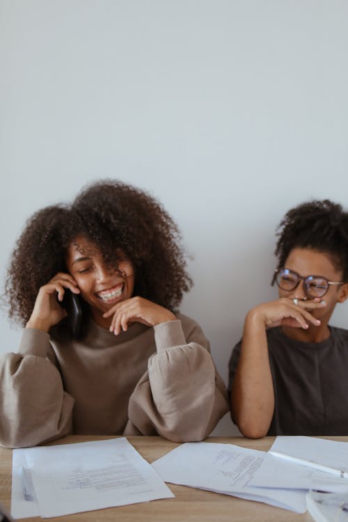 Free Young Women Laughing and Sitting Together Stock Photo