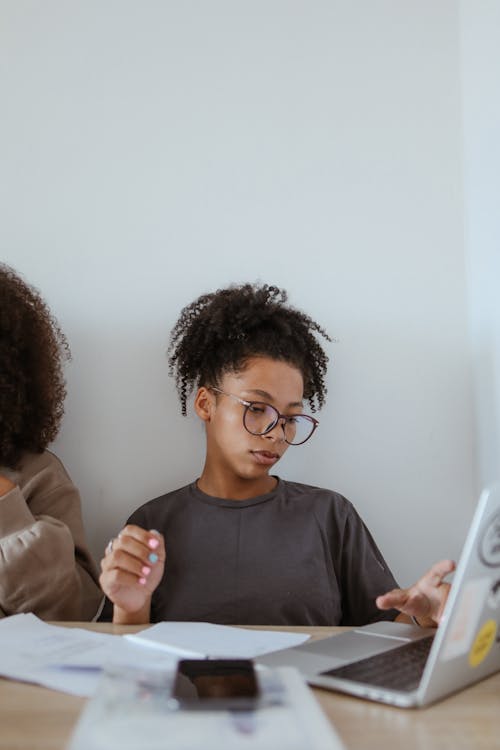 Young Woman in Gray Shirt Sitting and Using a Computer Laptop