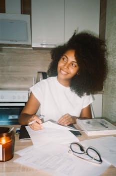 Smiling woman writing at home office with candlelight ambiance.