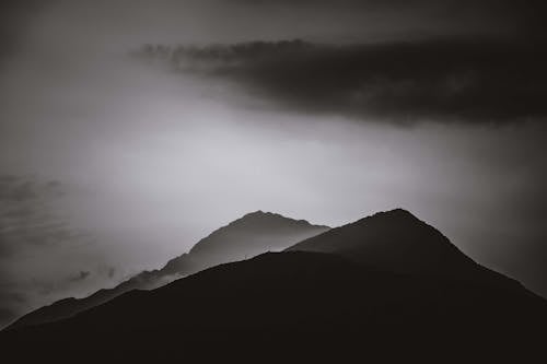 Silhouettes of mountain peaks under cloudy sky