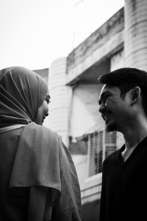 Free A candid black and white portrait of two individuals smiling and conversing outdoors. Stock Photo
