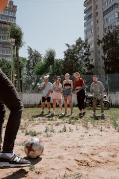 A group of young adults enjoying a casual soccer game in an urban outdoor setting.