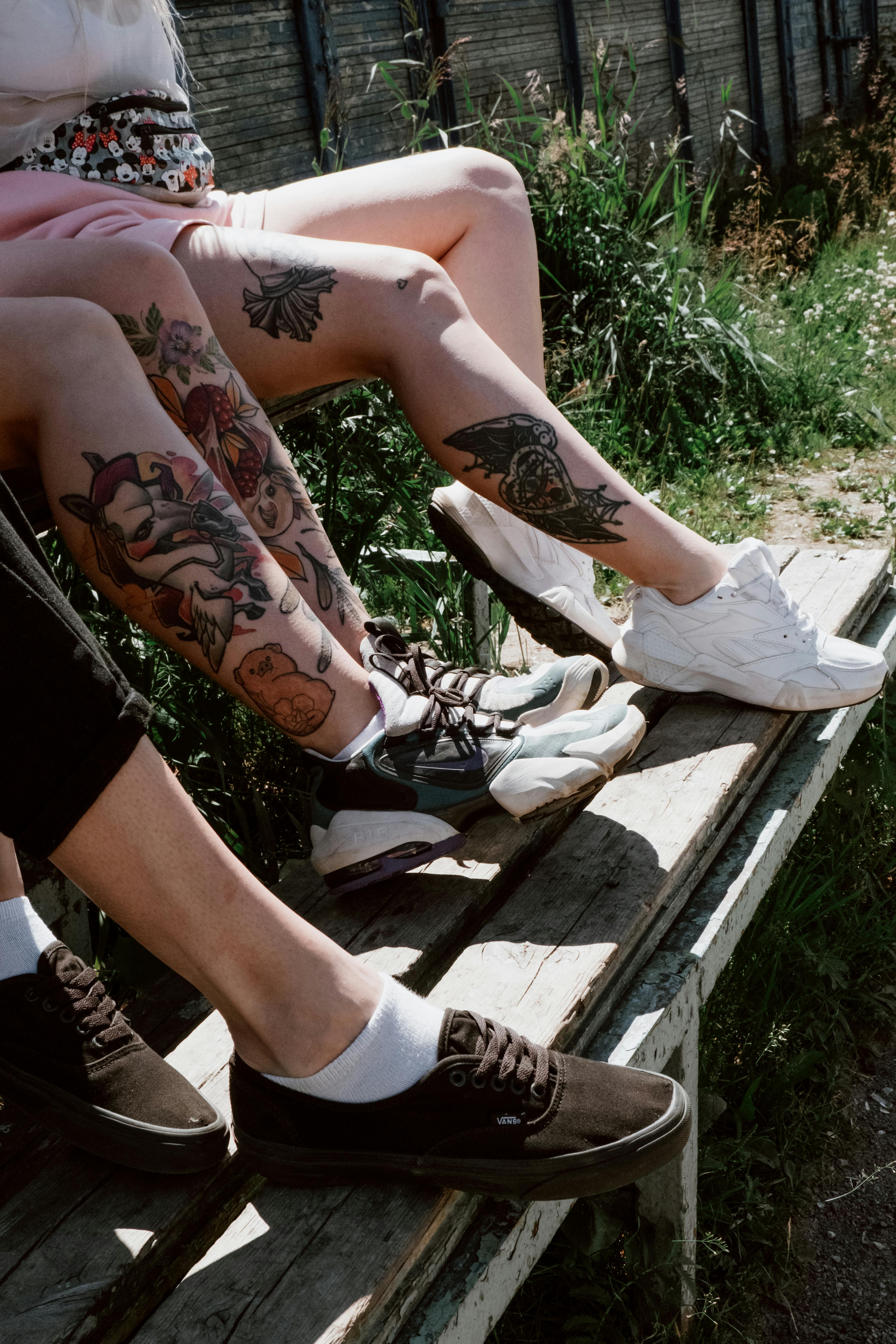 Women with Leg Tattoos Sitting on the Bleachers · Free Stock Photo