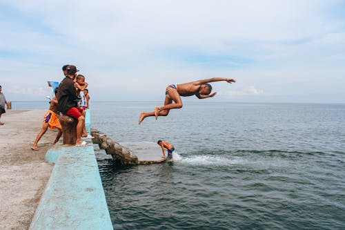 Boy Jumping into Sea from Pier
