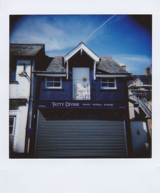 A quaint blue house with closed shutters under a clear sky, exuding vintage charm.