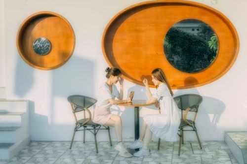 Free Full body of tender Asian girlfriends at small table against wall with mirrors on modern terrace Stock Photo