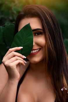 一幅微笑女子的明亮肖像半掩于树叶之后，展现出自然的美丽与优雅