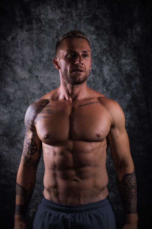 Free Studio portrait of a muscular man showing defined physique and tattoos. Stock Photo