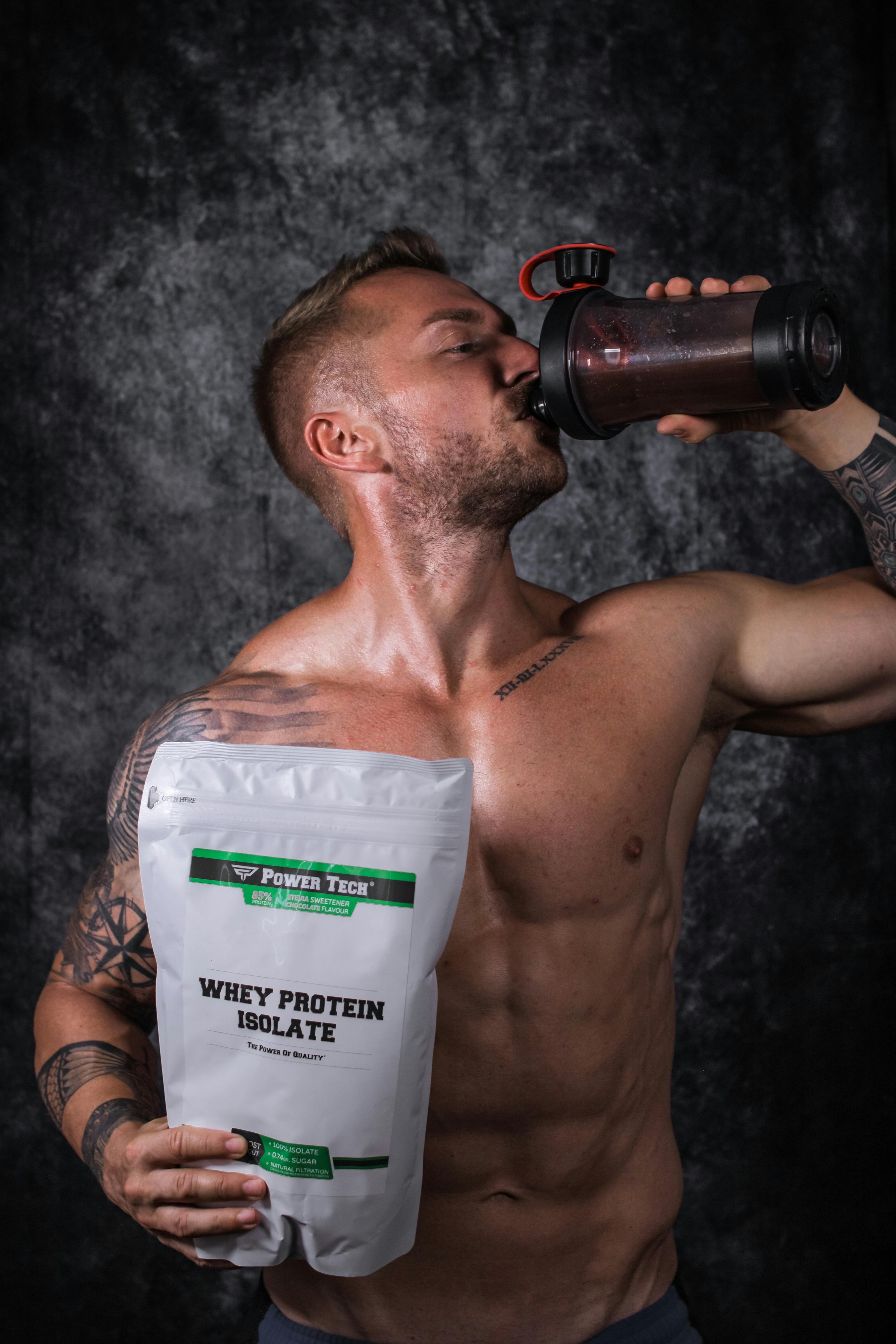 a muscular man drinking from a tumbler