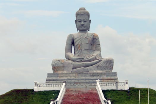 Majestic stone Buddha statue seated outdoors with a cloudy sky backdrop.