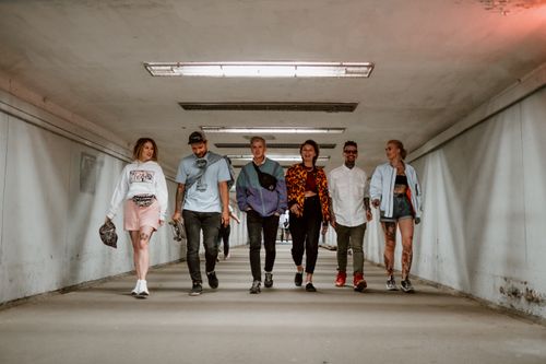 Free Casual group of young adults walking together in an urban tunnel, enjoying a relaxed day. Stock Photo