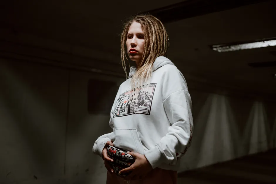 Femme en hoodie oversize blanc adoptant un style streetwear sombre et urbain