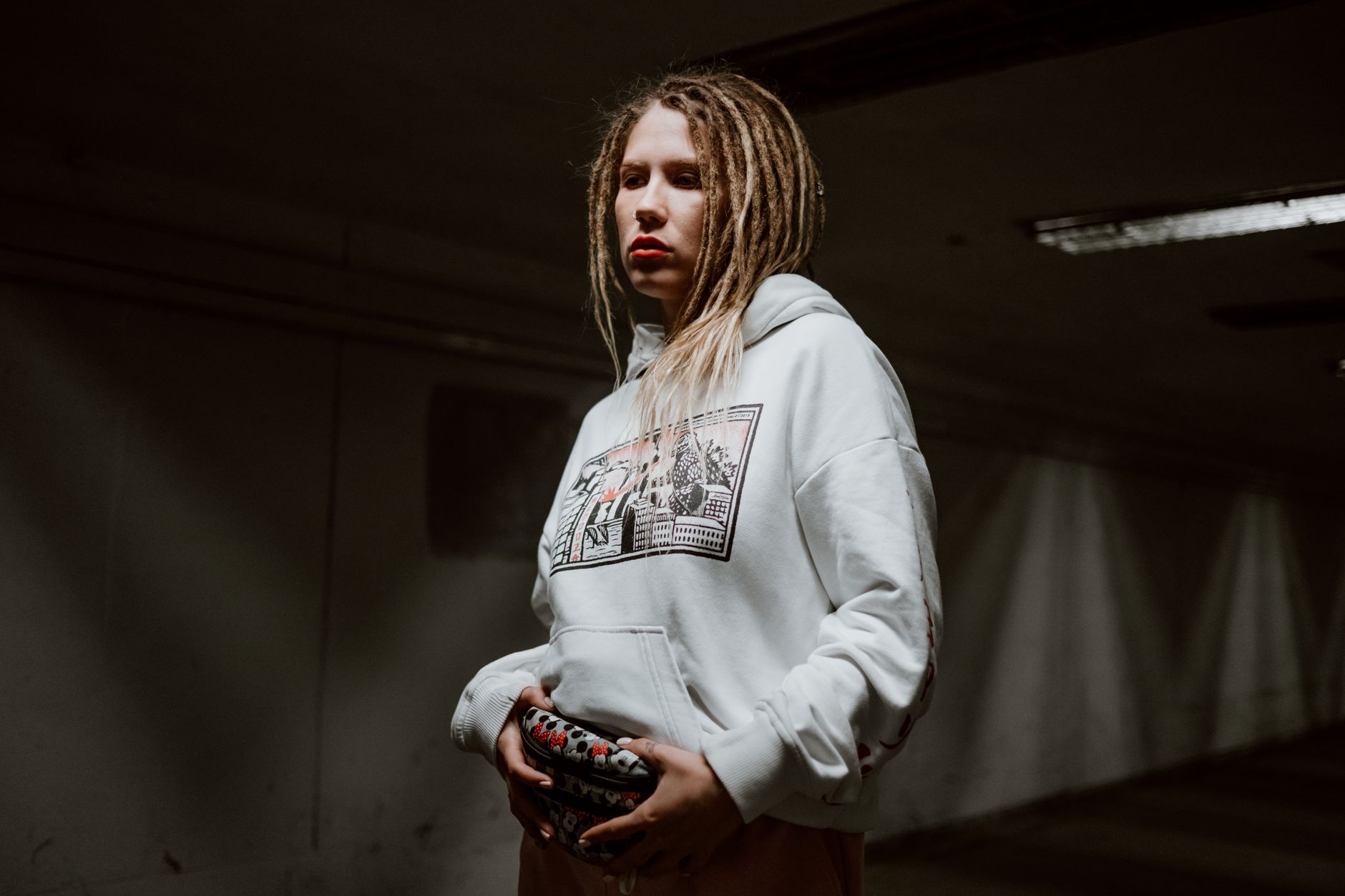 Femme en hoodie oversize blanc adoptant un style streetwear sombre et urbain
