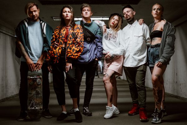 A group standing in a concrete underpass with bags and boards — photo by cottonbro studio on Pexels
