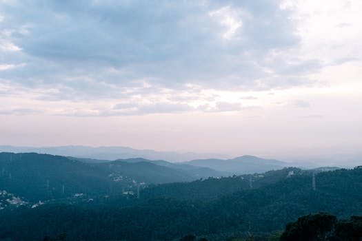 Serene mountain view with mist and clouds during dusk offering a tranquil and picturesque scene.
