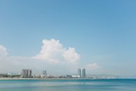 阳光明媚的日子里，沿着宁静的海滩，可以看见城市天际线的广角视图