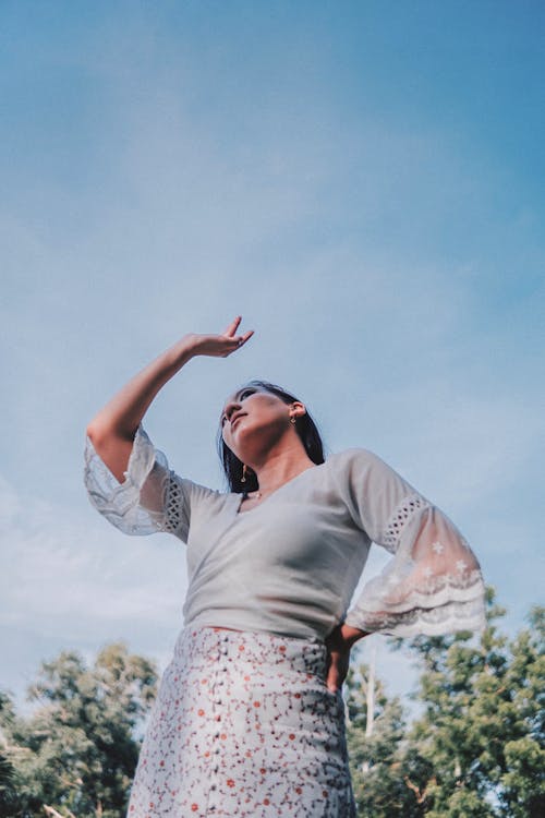 Trendy woman with raised arm under cloudy sky