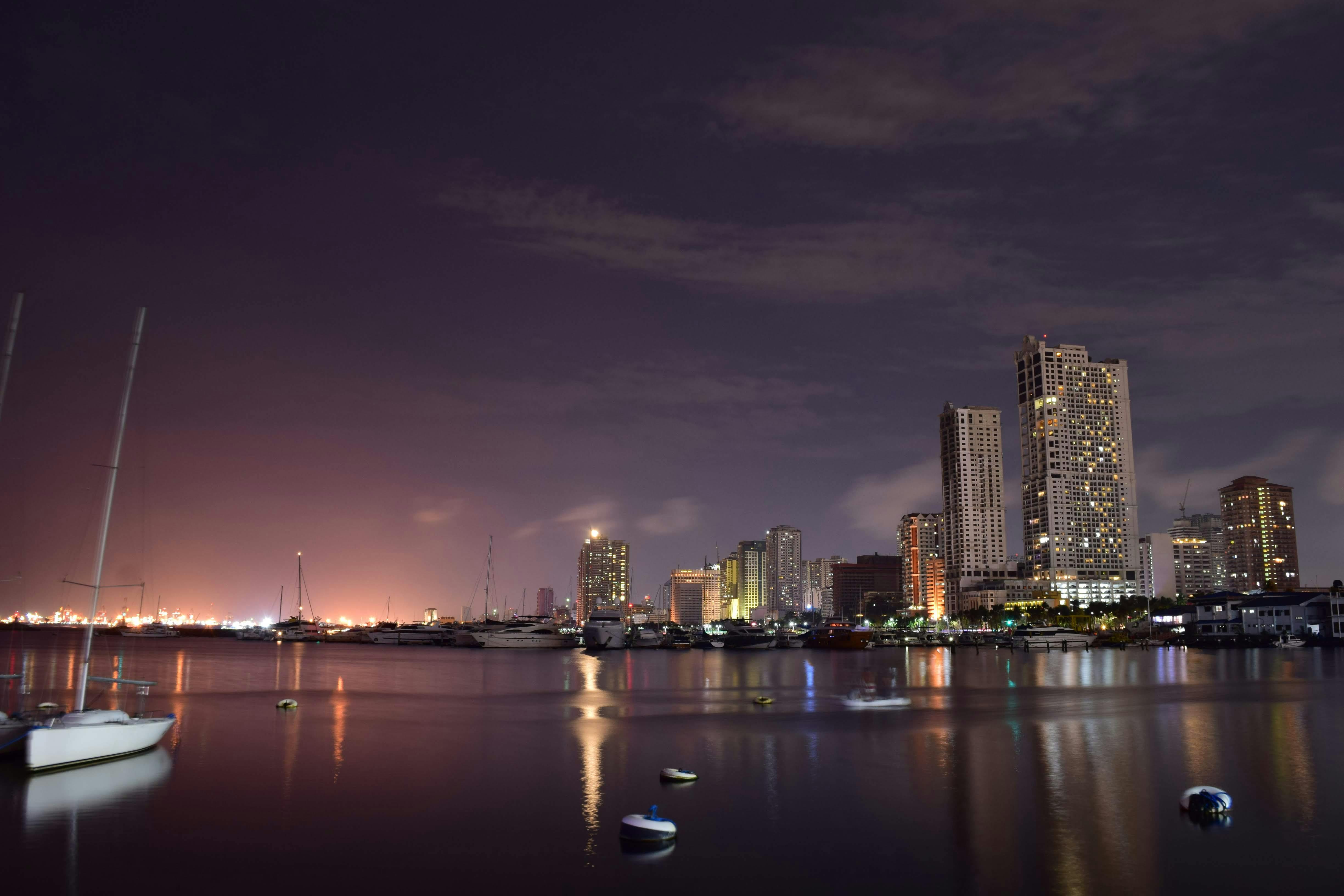 modern buildings on sea shore with moored yachts against sunset sky