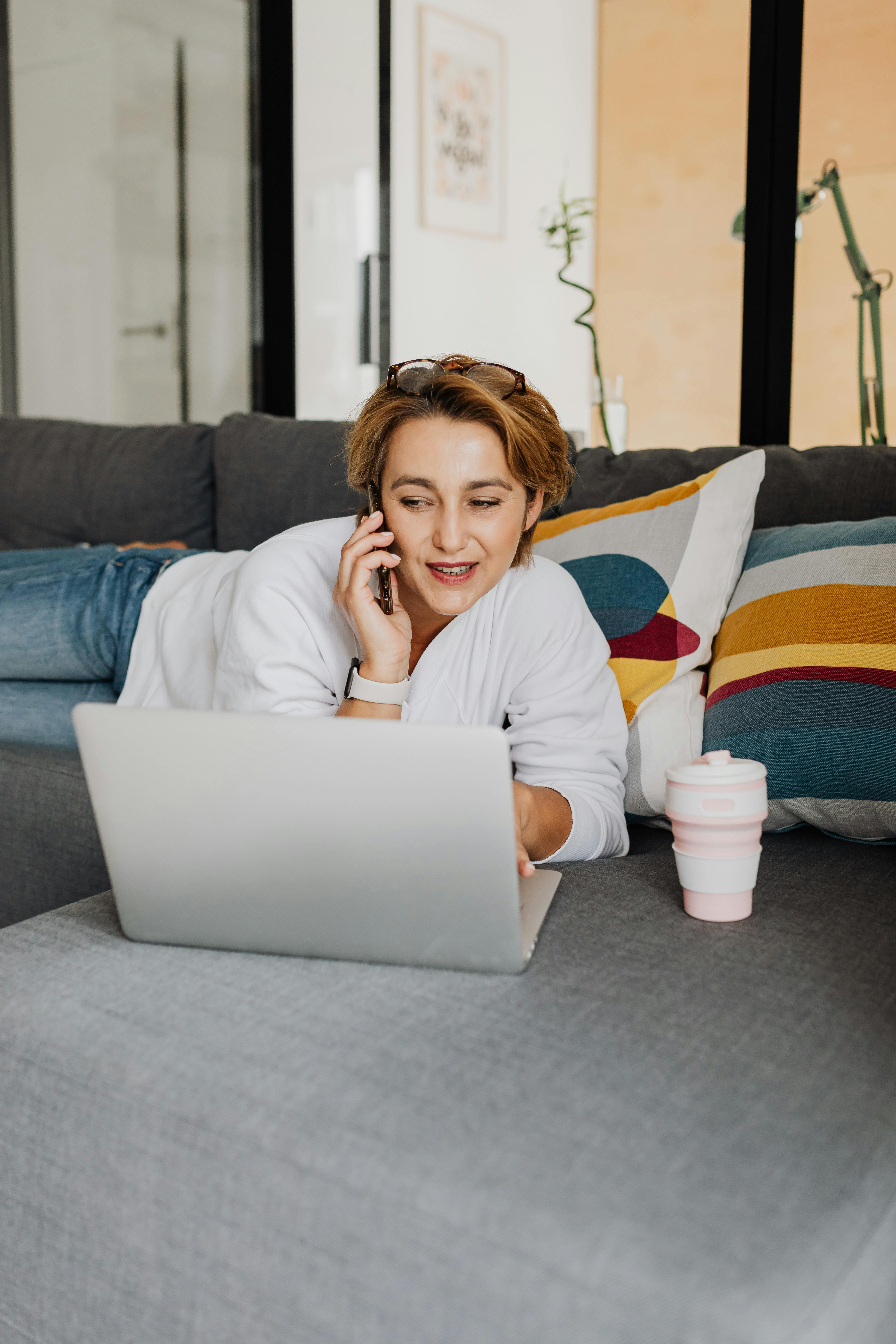 short haired woman lying on a couch talking on the cellphone