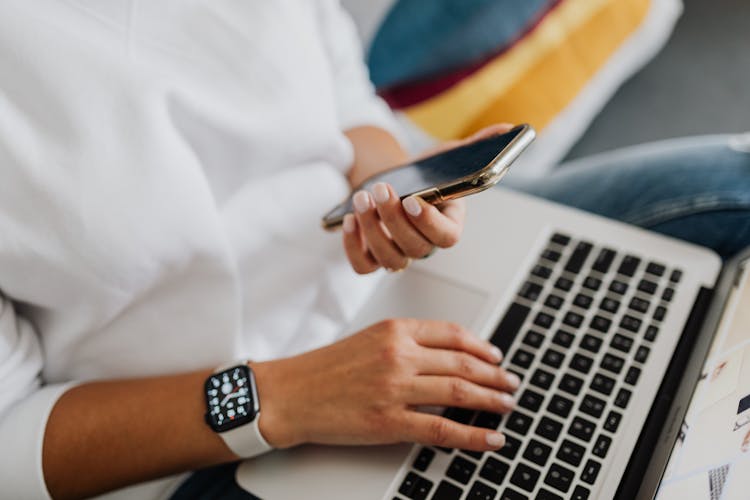 Person Holding A Cellphone And Laptop