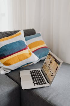 A modern laptop on a stylish gray couch with colorful pillows, perfect for home office inspiration.