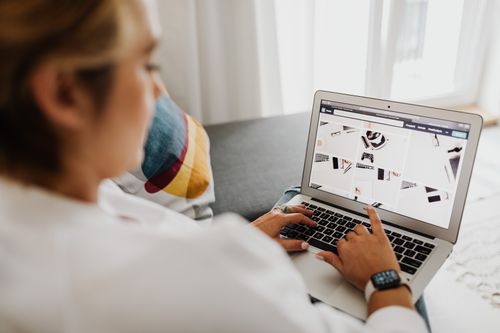 Free Person using laptop in a cozy home setting, focusing on digital content browsing. Stock Photo