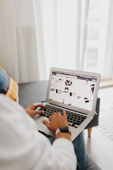 Person using a laptop in a well-lit room, depicting a comfortable home office environment.