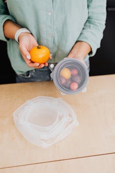 Person holding fresh vegetables and using eco-friendly storage in kitchen.