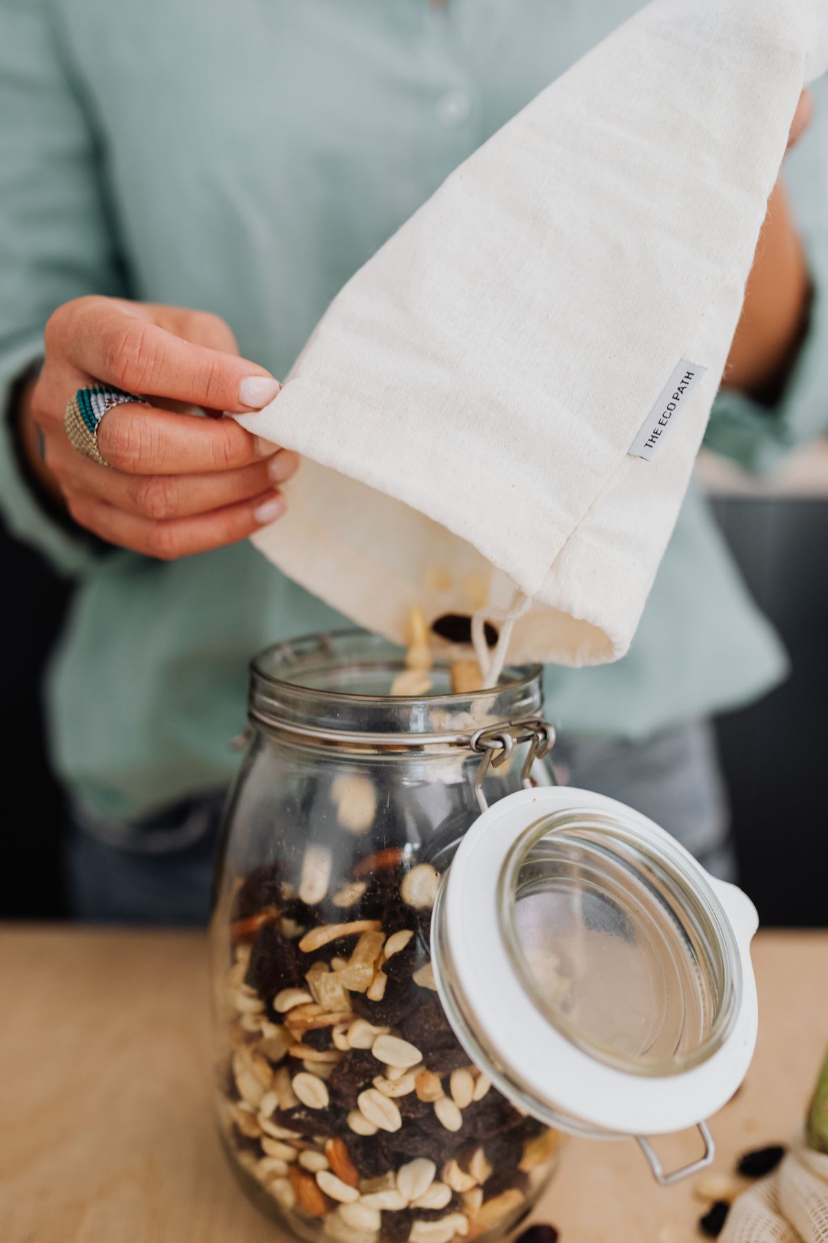 Cotton drawstring bag held open while seeds are poured in, representing the certified cotton seed bag products that OEKO-TEX Standard 100 covers for UK garden retailers and US seed companies