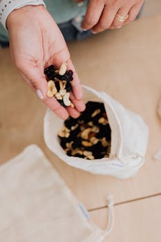 A hand holding a mix of nuts from a cotton bag, promoting zero waste lifestyle.