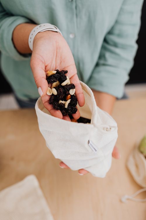 Free Close-up of a woman's hand holding a mix of raisins and nuts in a fabric bag, promoting healthy snacking. Stock Photo