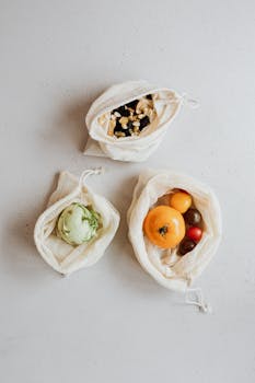 Top view of fruits, vegetables, and nuts in eco-friendly cotton bags promoting zero waste lifestyle.