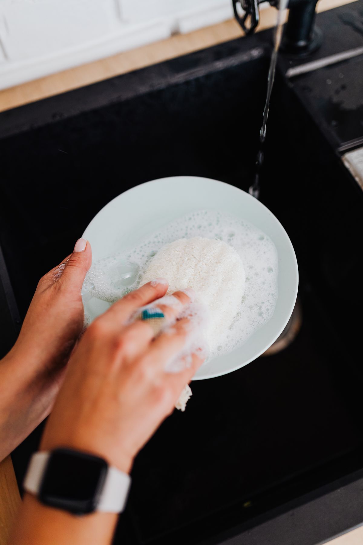 Are silicone dish scrubbers better than sponges — woman washing dishes at a kitchen sink