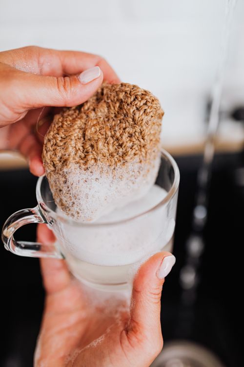 Free Close-up of hands cleaning a glass cup with a natural sponge and foam. Stock Photo