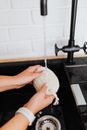Hands Holding Item over Water in Sink
