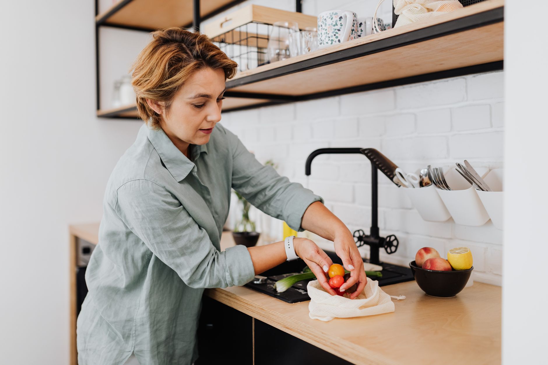 Woman preparing fresh vegetables in a sleek kitchen setting, showcasing culinary activities.