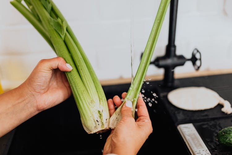 Woman Washing Celery In Kitchen 