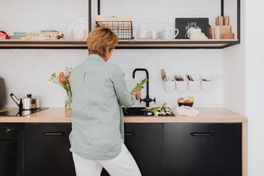 A woman standing at a kitchen counter preparing fresh vegetables. Modern and vibrant home interior.