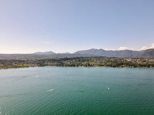 Motorboats on sea near green ridge under sky