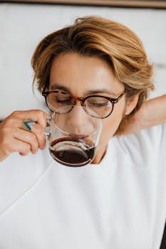 Close-up of a woman in glasses enjoying a morning coffee. Relaxed and serene.