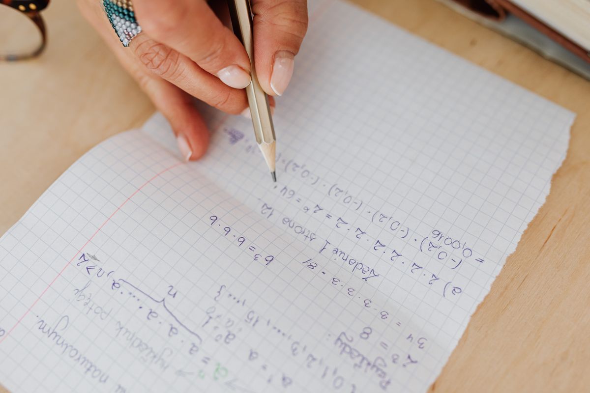 شخص يكتب معادلات على ورق شبكي
