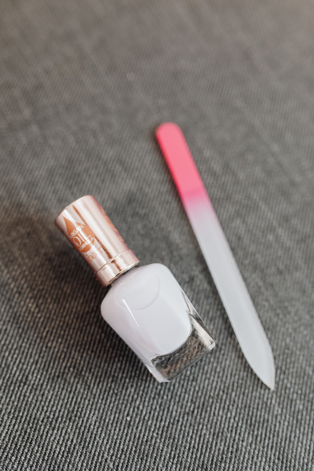 Nail polish and a glass nail file presented in a minimalist beauty setting