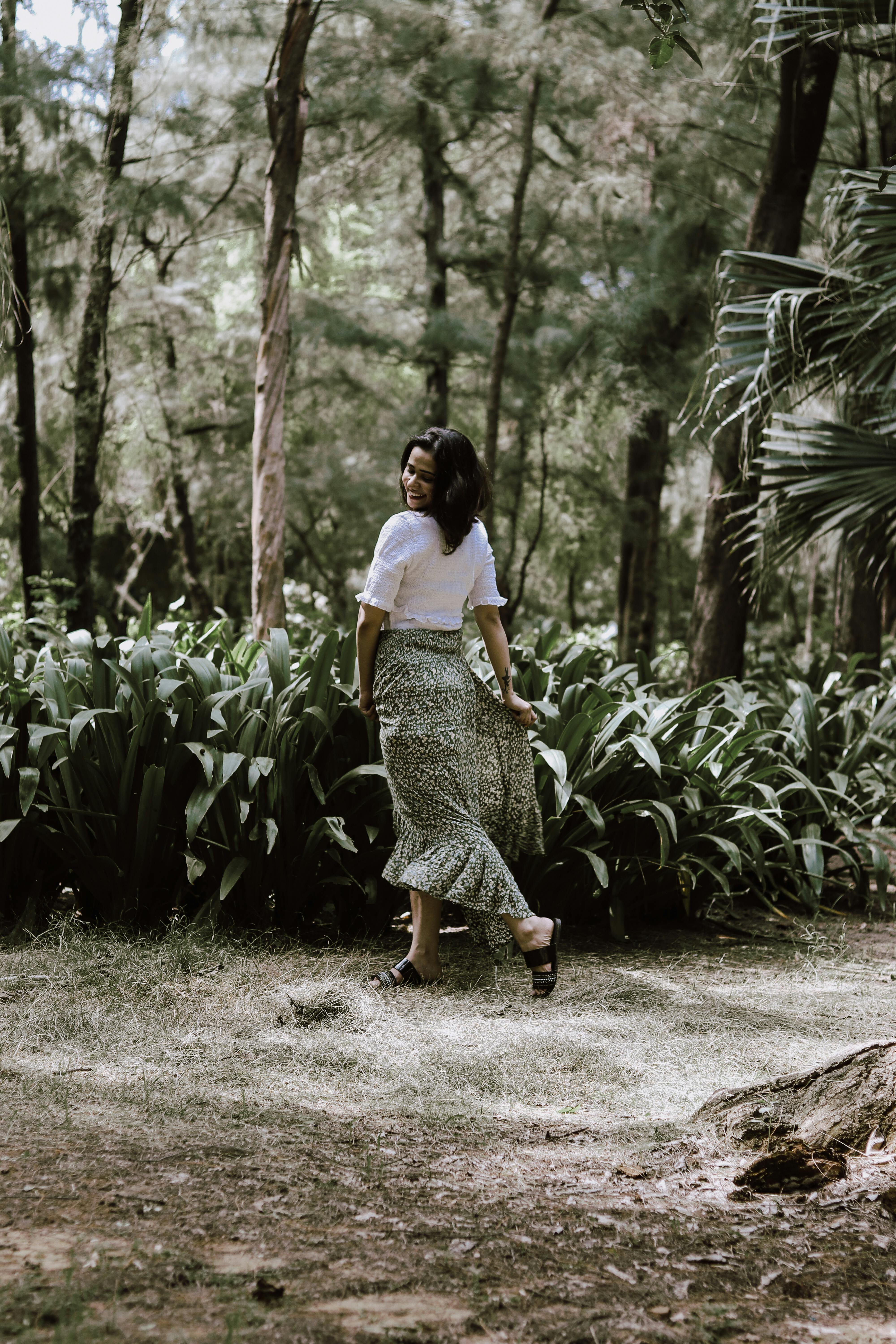 A woman walking gracefully through a lush forest path in New Delhi, India.