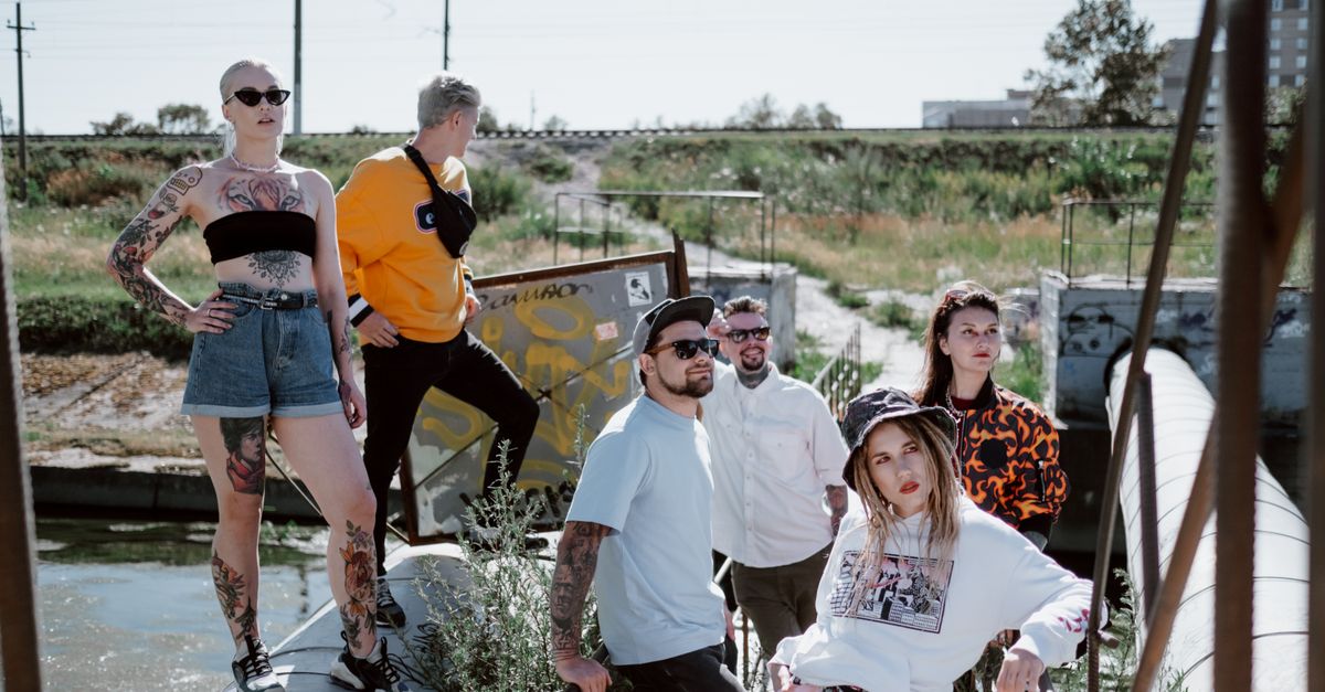 Fashionable group posing in streetwear by an industrial outdoor area.