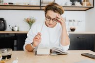 Woman Reading Book at Breakfast