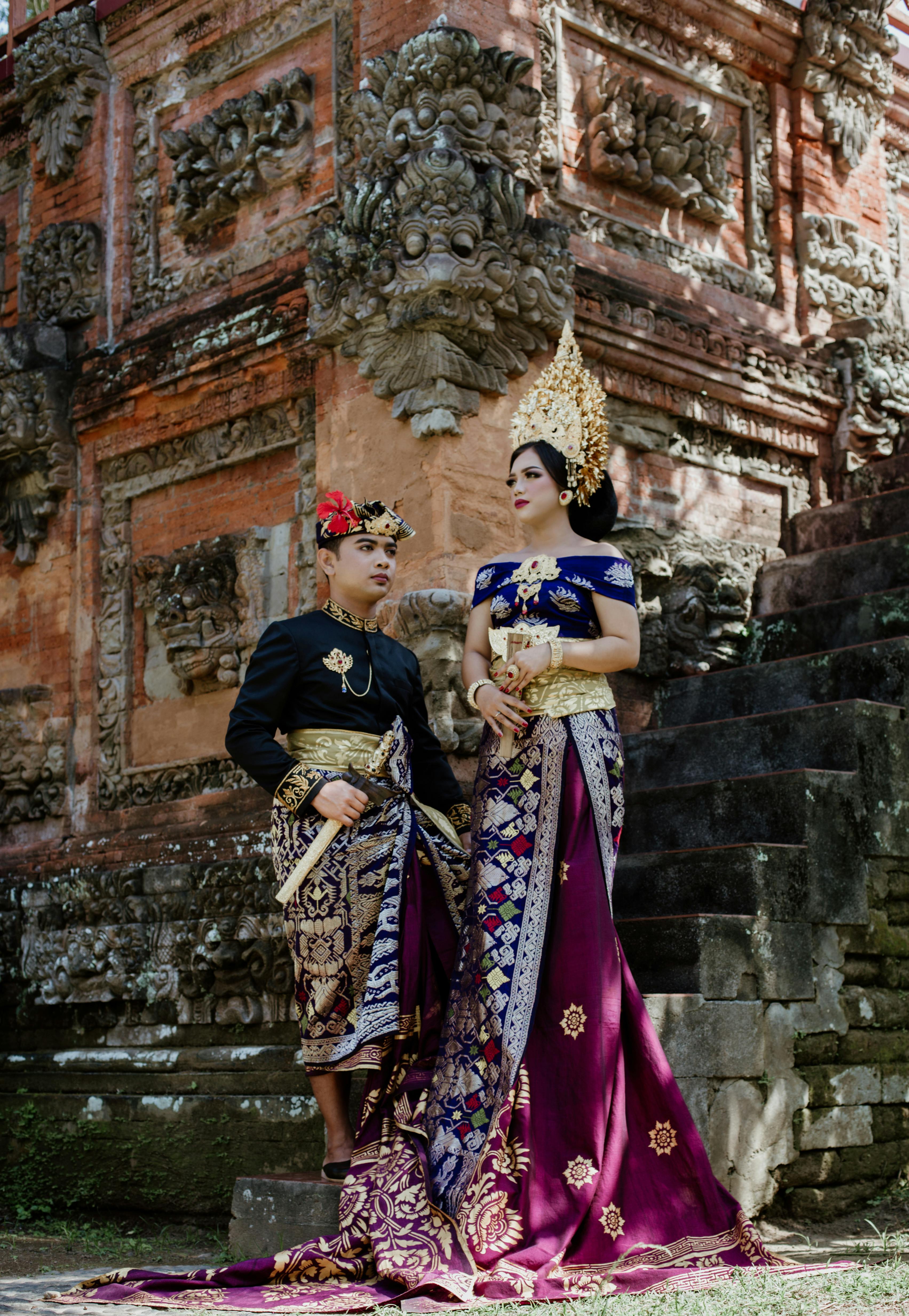 trendy ethnic couple in traditional clothes on stairs near temple